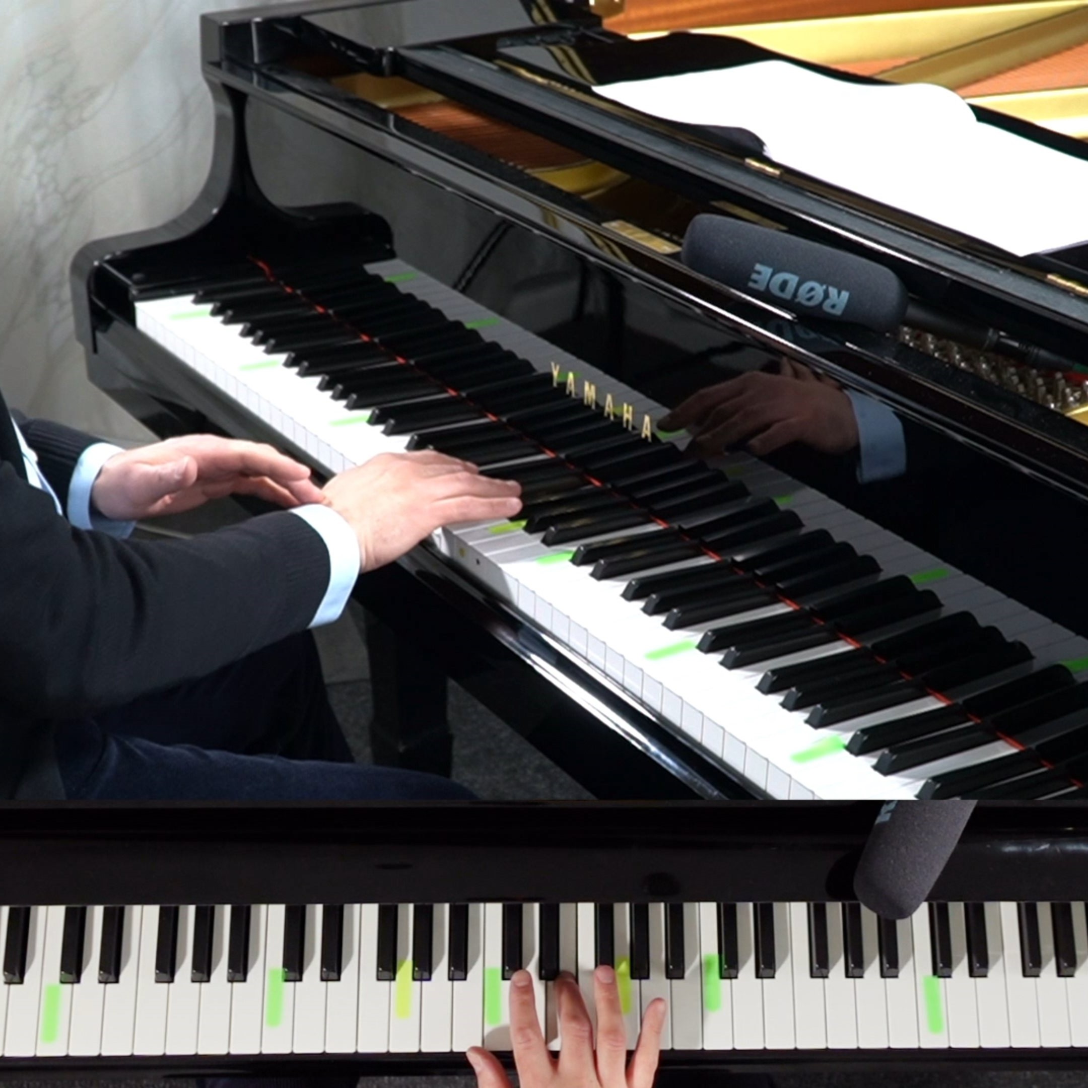 Nahaufnahme eines schwarzen Yamaha-Flügels mit Mikrofon, gespielt von Händen in einem Anzug.
